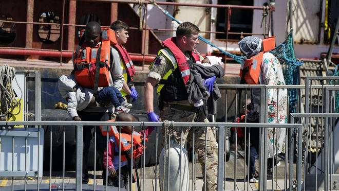 A soldier carries a child from a group of people thought to be migrants are brought in to Dover