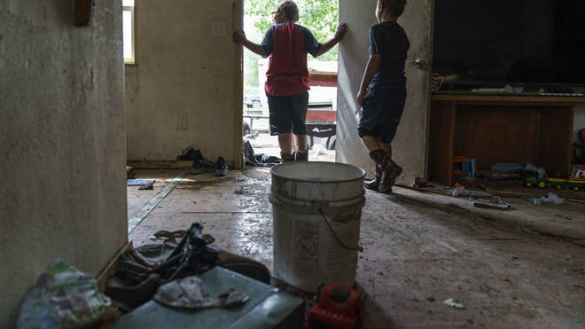 Gavin Holmes, 9, left, and his brother, Tyce, 7, stand in their damaged home as the family packs up while forced to leave after severe flooding in Fromberg, Mont., Friday, June 17, 2022.