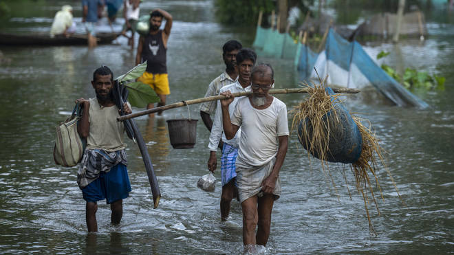Flood-affected people walk to safer places from their marooned Tarabari village, west of Gauhati, in the north-eastern Indian state of Assam