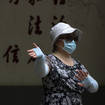 A woman wearing a face mask exercises at a public park in Beijing