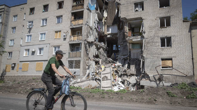 A man rides a bicycle past a building damaged in Russian shelling in Bakhmut, Donetsk region, Ukraine