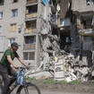A man rides a bicycle past a building damaged in Russian shelling in Bakhmut, Donetsk region, Ukraine