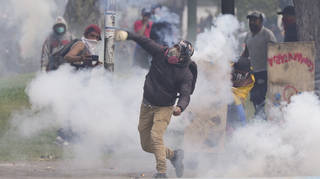 A demonstrator hurls a tear gas canister back at police during protests against the government of President Guillermo Lasso and rising fuel prices in Quito, Ecuador