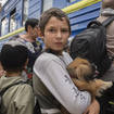 A boy holds his pet dog as his family evacuated from the war-hit area gets on an evacuation train in Pokrovsk, eastern Ukraine, Saturday, June 25, 2022
