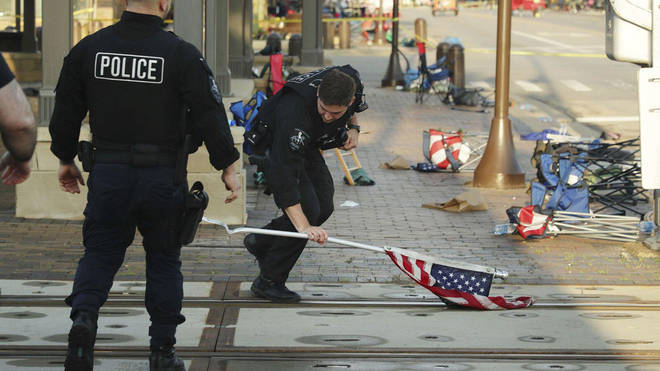 Police clear American flags from the scene of the shooting at Highland Park in Chicago on Monday
