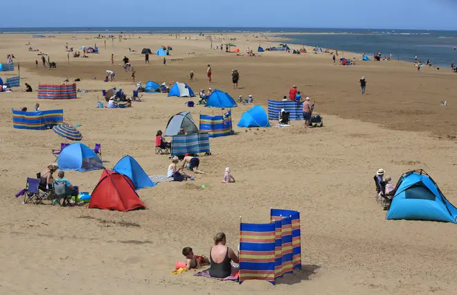 Visitors enjoy the large sandy beach, sunbathing on July 11, 2022 in Wells-next-the-Sea, United Kingdom
