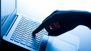 A woman’s finger pressing a key on a laptop keyboard