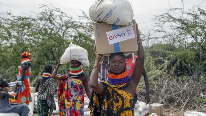 Local residents carry boxes and sacks of food distributed by the United States Agency for International Development in Kachoda, Turkana area, northern Kenya