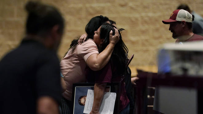 A family member holds a portrait of shooting victim Jackie Cazares as she is hugged following a special meeting of the Board of Trustees of Uvalde Consolidated Independent School District
