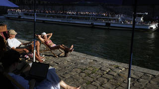 Parisians and tourists take sunbathe along the Seine River amid hot weather in Paris, France