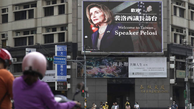 People walk past a billboard welcoming US House Speaker Nancy Pelosi in Taipei, Taiwan