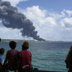 People watch a huge plume of smoke caused by a blaze after lightning struck an oil storage tank in Cuba