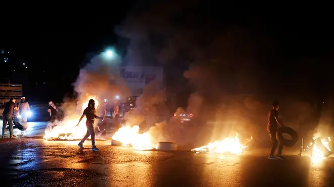 Palestinian demonstrators burn tyres as they block the main street near the Hawara checkpoint in protest over Israeli airstrikes