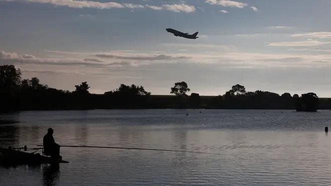 Man fishing in Yeadon Tarn as an aircraft takes off from Leeds Bradford Airport