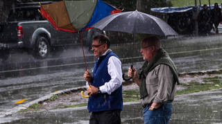 Men walk in the rain with umbrellas
