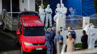 New Zealand police investigators work at a scene in Auckland after bodies were discovered in suitcases