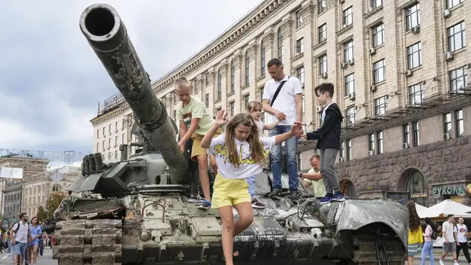 Children play on a destroyed Russian tank put on display in a square in Kyiv