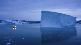 A boat navigates at night next to large icebergs in eastern Greenland in 2019