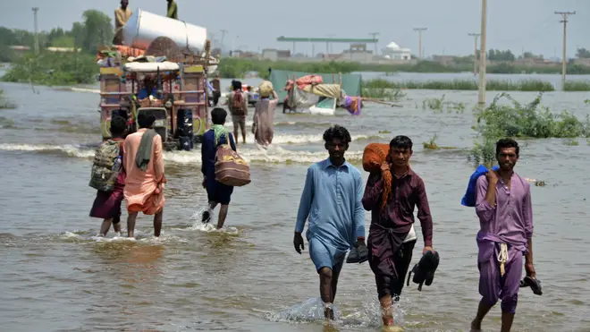 People wade through a flooded area of Sohbatpur, a district of Pakistan’s south-western Baluchistan province