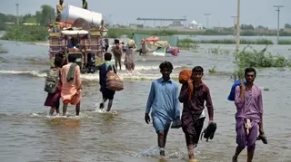 People wade through a flooded area of Sohbatpur, a district of Pakistan’s south-western Baluchistan province