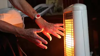 An elderly woman with her electric fire on at home