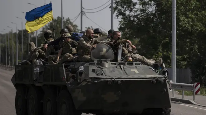Ukrainian servicemen ride on an armoured vehicle