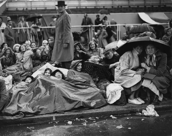 Crowds sit on The Mall in heavy rain before the Queen's coronation in 1953