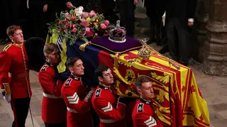 The Queen's coffin is draped in a flag and covered with royal jewels and flowers