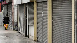 A woman walks past shuttered shops