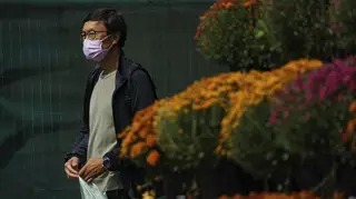 A person wears a mask while walking past a flower display in front of a supermarket in Front Street East, Toronto