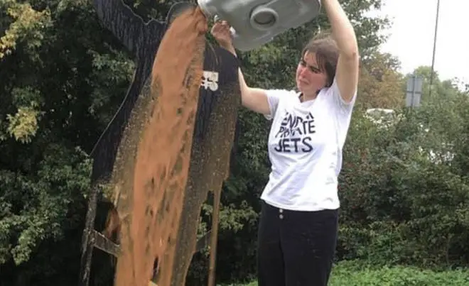 The activist carries out her dirty protest on the statue of Sir Tom Moore. Picture: End Private Jets/Twitter