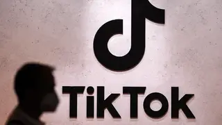 A person passes a TikTok logo