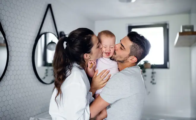 Mother and father kissing baby stock image Getty