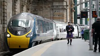 A piper performs next to an Avanti train in Glasgow