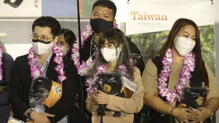 First group of foreign travellers hold souvenirs after arriving at Taoyuan International Airport in Taoyuan, Northern Taiwan