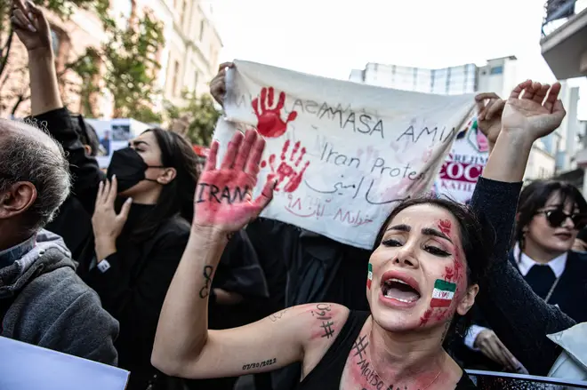 A protester with the Iranian flag painted on her face raises...