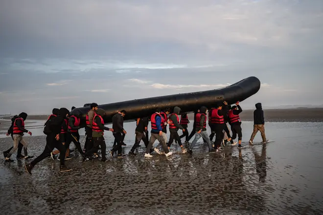 Migrants carry a smuggling boat on their shoulders as they prepare to embark