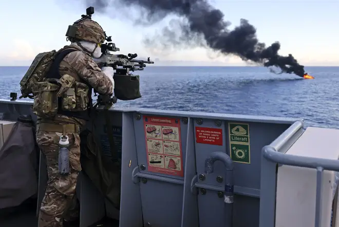 A Royal Navy sailor aims at the burning target