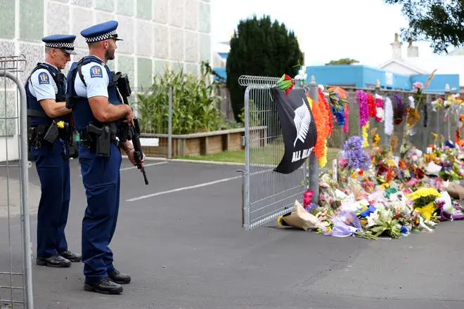 Two police officers stand near tributes to the victims of a shooting in Christchurch, New Zealand