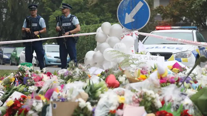 Two police officers stand near tributes to victims of the New Zealand terror attack