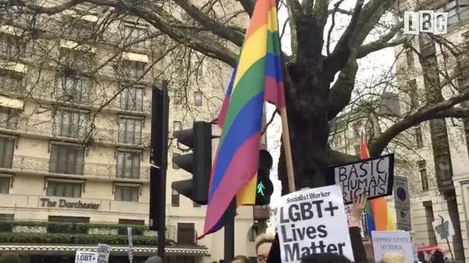 An LGBT flag is waved by protesters outside the Dorchester Hotel