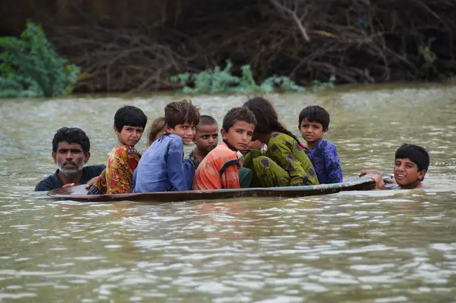 Children in Pakistan moving through floodwater this August