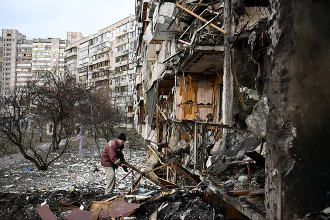 A man clears debris at a damaged residential building in Kyiv