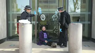 Police speak to a climate change protester who is glued to the Shell Centre.