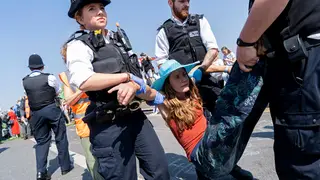 Police officers arrest and carry away a climate change protester who was blocking Waterloo Bridge