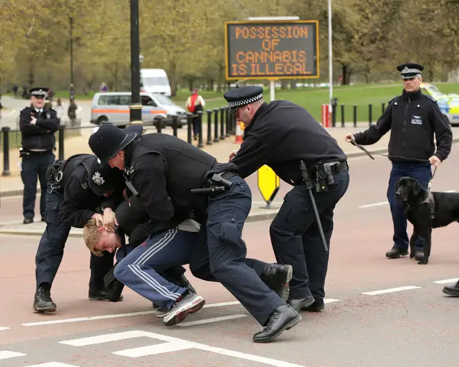 Police restrain a man at an entrance to Hyde Park, central London, during a '420 Celebration' pro-cannabis event