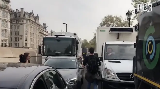 The lorry driver points to the tailback behind him as he rants to a campaigner over the disruptions facing Londoners