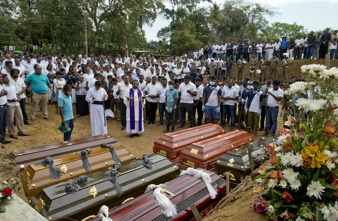 A priest conducts religious rituals during a mass burial for Easter Sunday bomb blast victims