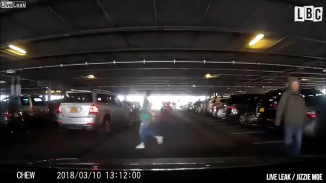 A woman runs into a parking space to hold it for another driver.