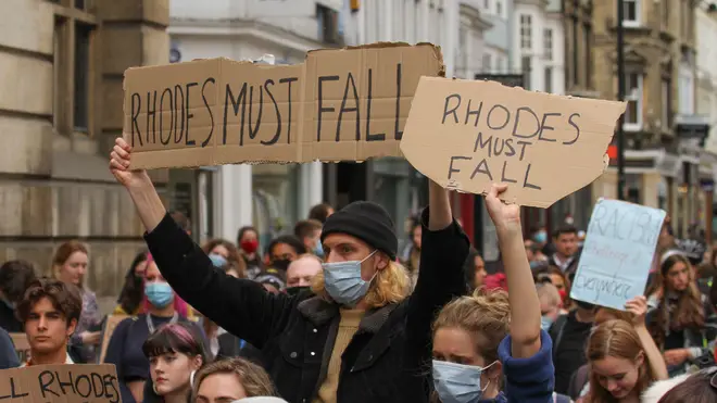 Protesters hold Rhodes Must Fall placards during a demonstration.